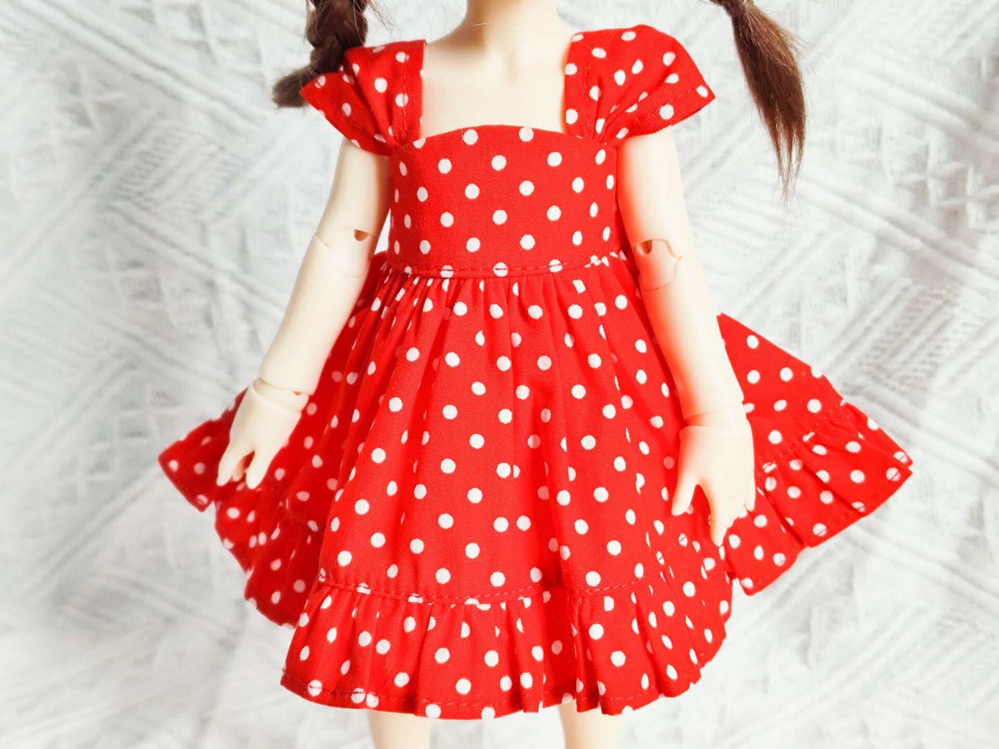 Close-up detail of 1/6 BJD YoSD doll clothes, classic red and white polka dot pattern.