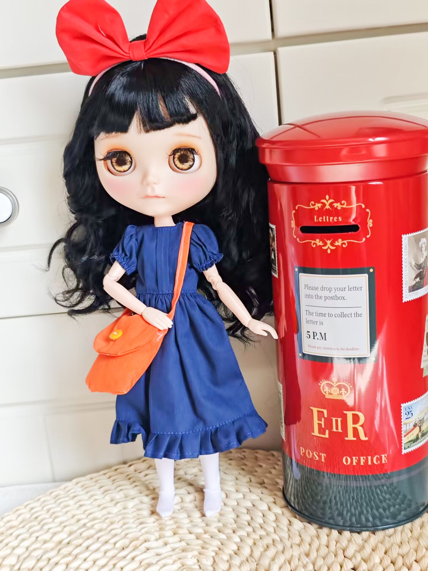 Handcrafted witch anime cosplay doll clothes styled on a curly black hair Blythe doll standing next to a vintage British red postbox prop.