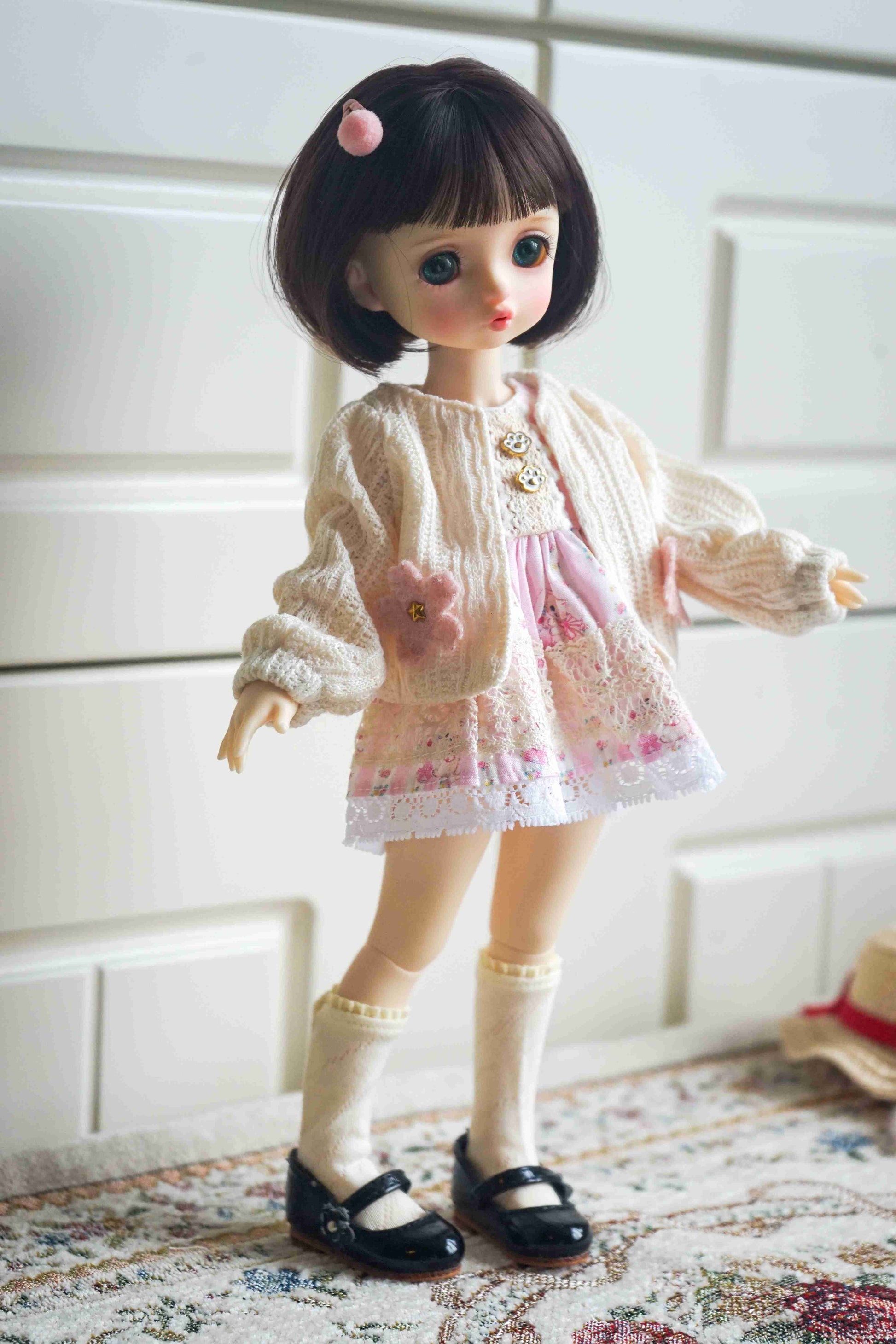 1/6 BJD YoSD doll wearing a handmade bear ear knit cardigan and floral pinafore set.