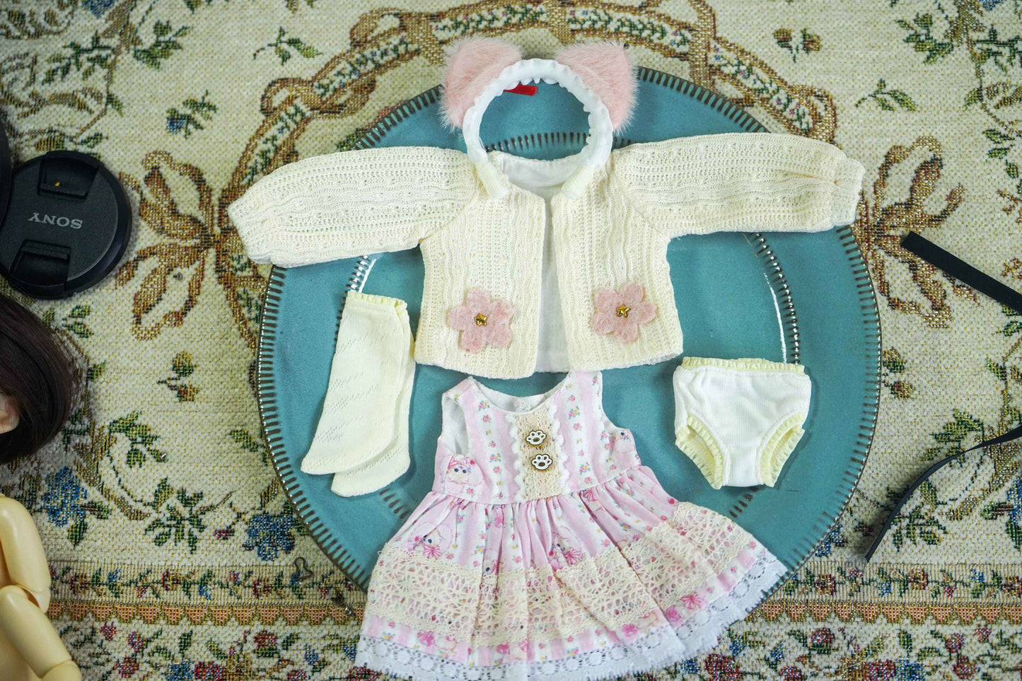 Product flat lay of the handmade bear ear cardigan, floral pinafore, and headband set.