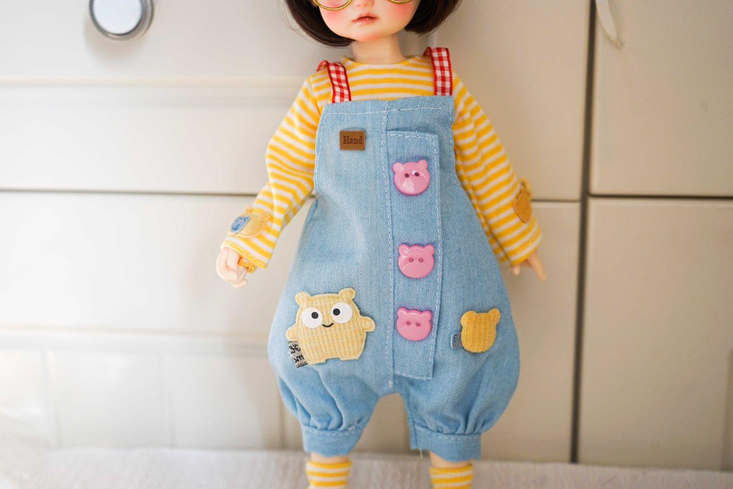 buttons-detail-03.jpg	Close-up of the denim overalls center section featuring pink bear buttons on a 1/6 BJD doll.