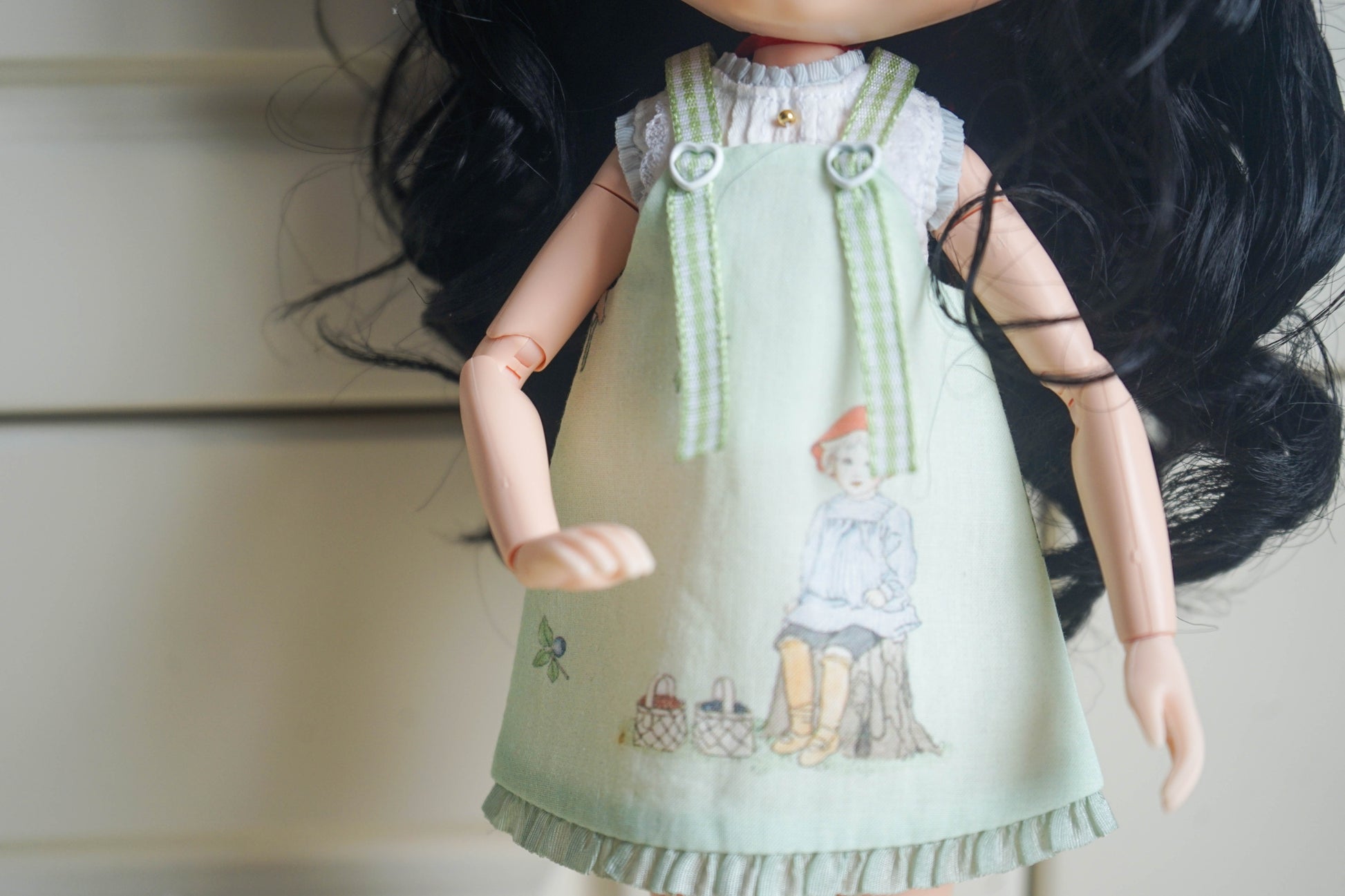 Detailed view of the vintage storybook illustration on a handmade doll pinafore dress.