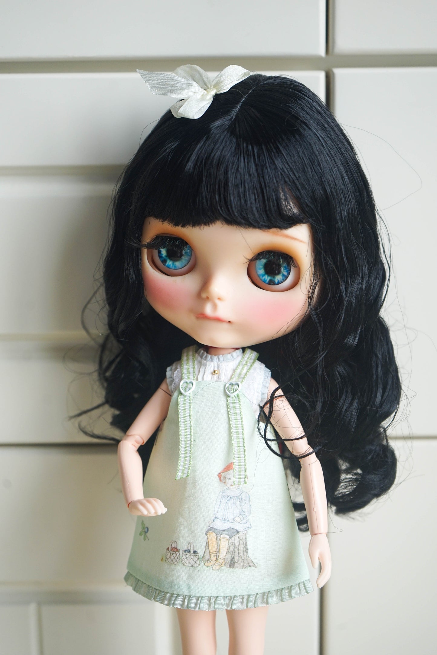 Side profile view of a handmade pastoral style pinafore dress on a Blythe doll.