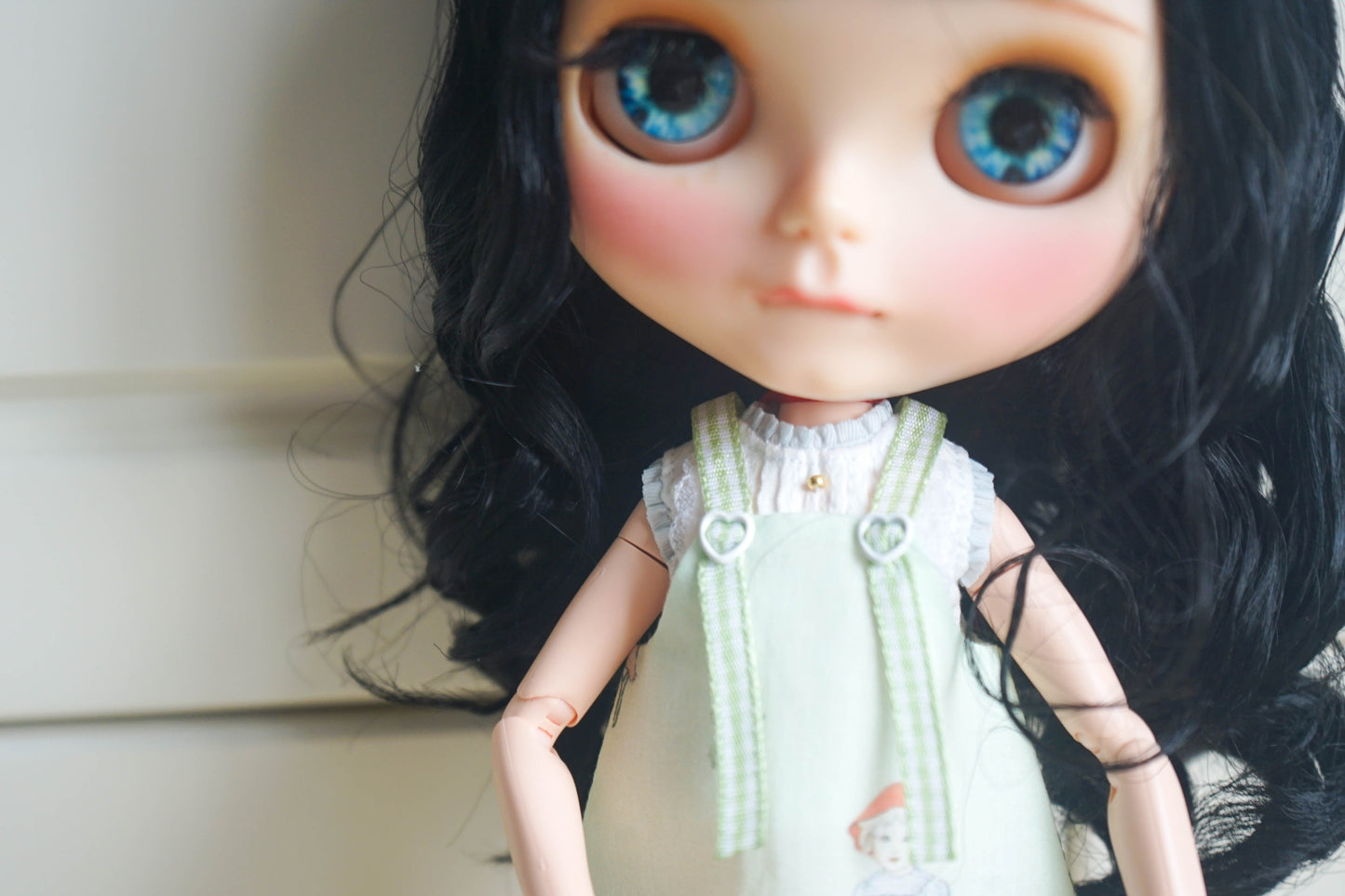Close-up of the heart button and strap details on a handmade doll pinafore dress