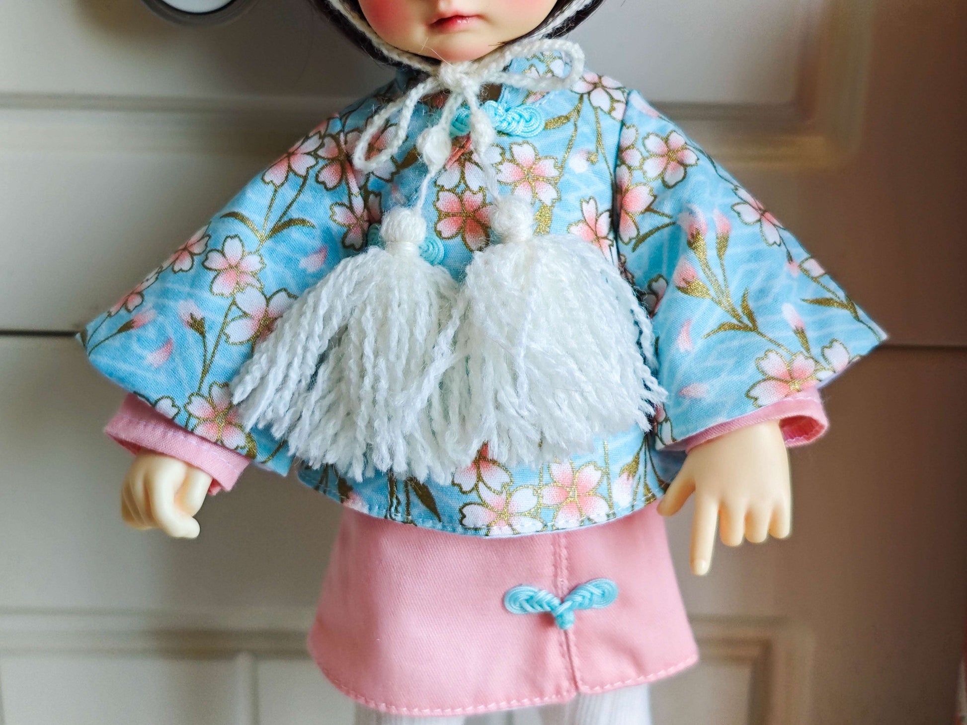 Close up of the exquisite handcrafted floral doll bandana featuring delicate hanging tassels.