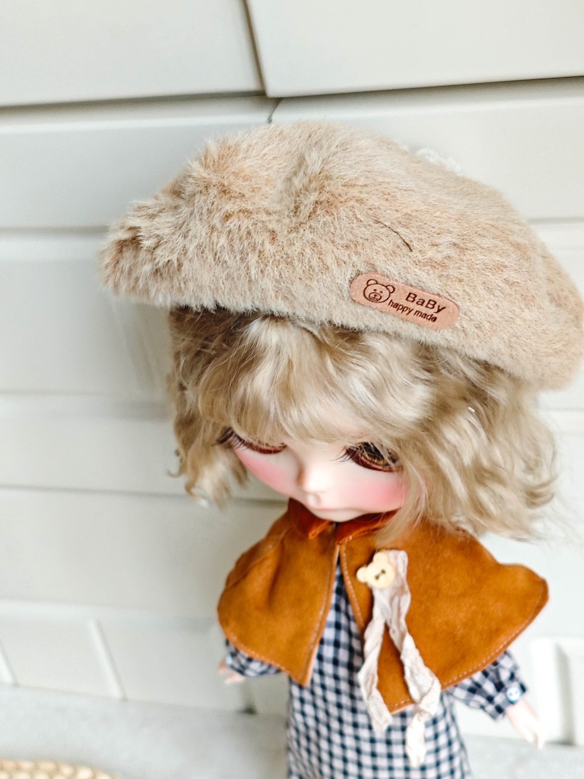 Close up of the red hooded cape with brown bow tie and the matching furry beret on the doll.