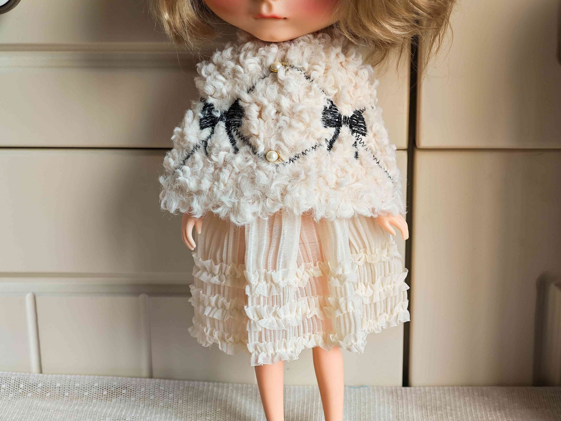 Close up of the premium white faux fur doll cape with a delicate ribbon bow closure.