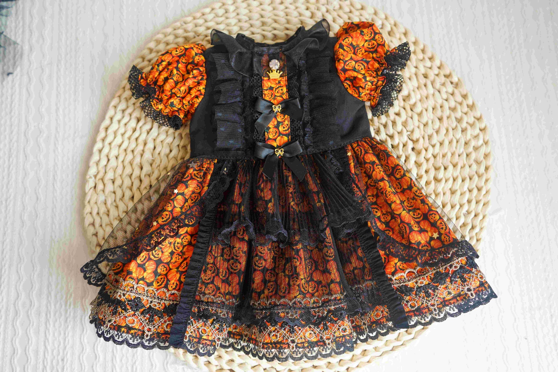 Flat lay product photography of the gothic pumpkin witch dress, showing the intricate skull buttons and layered hem.