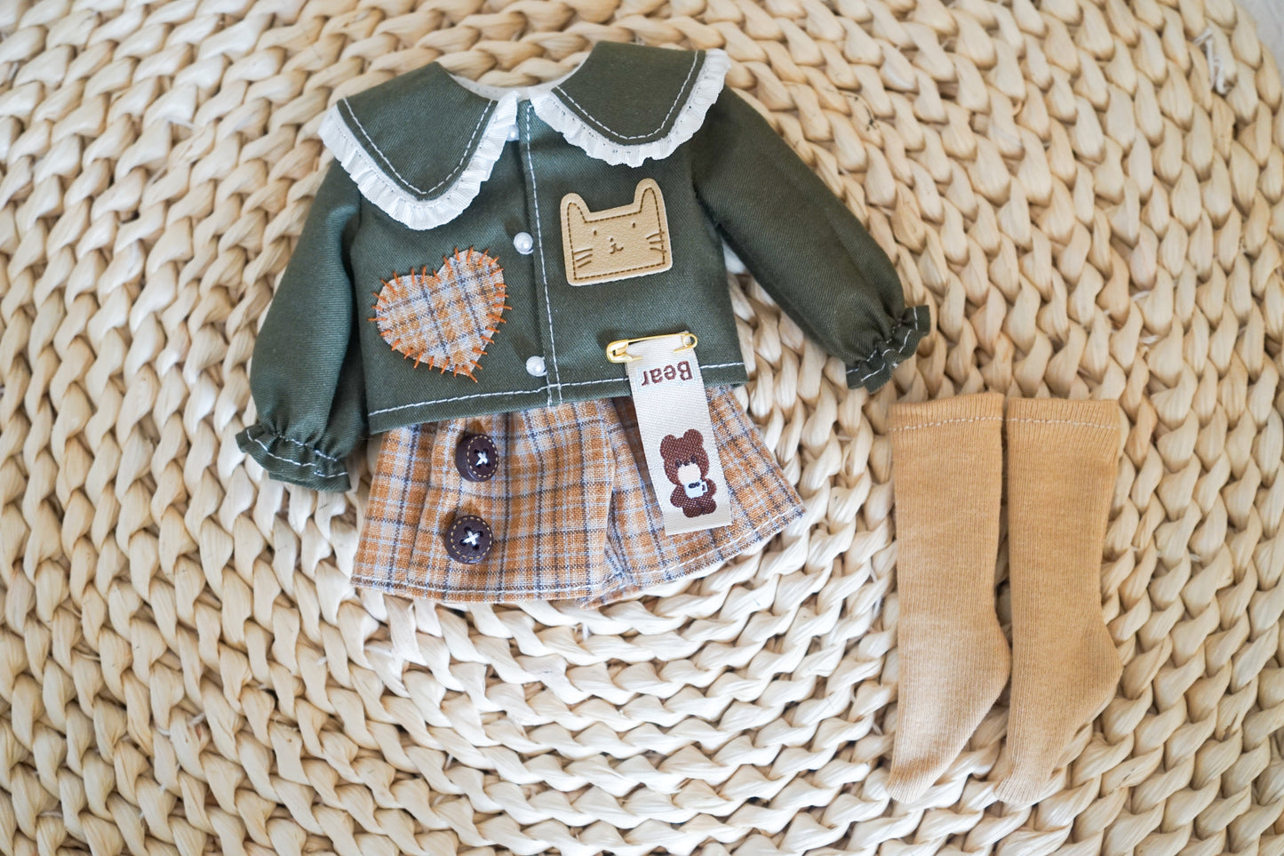 Flat lay of green cat patch shirt and plaid shorts set.