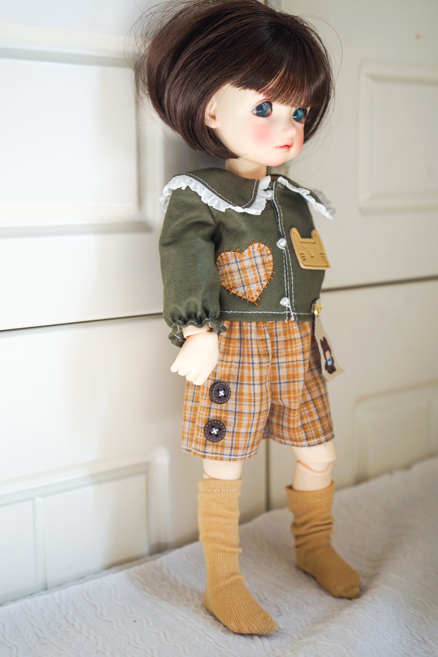 Side view of green cat patch shirt and plaid shorts on 1/6 BJD doll.