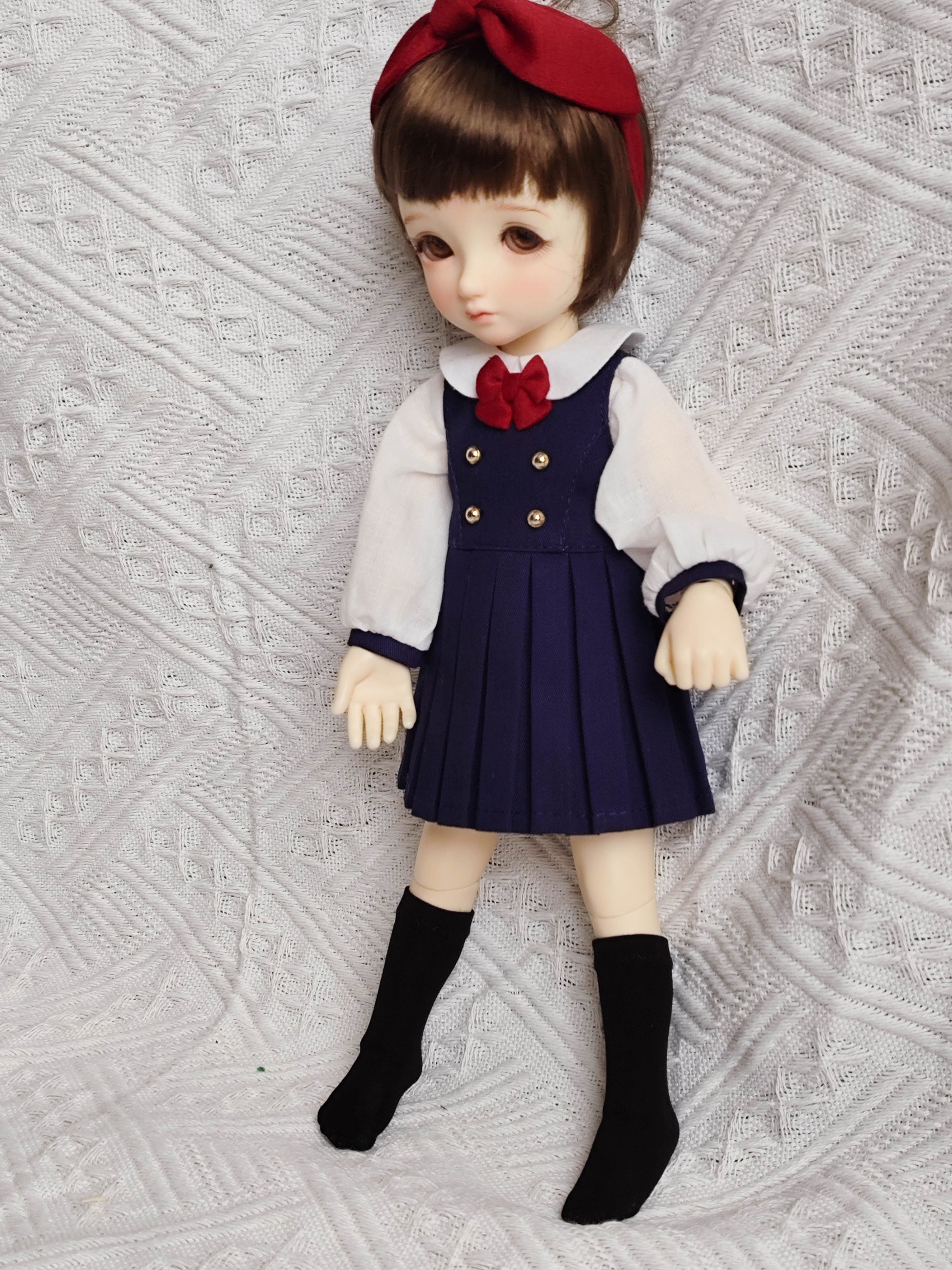 Side view of BJD doll in a preppy school uniform shirt and pleated skirt.