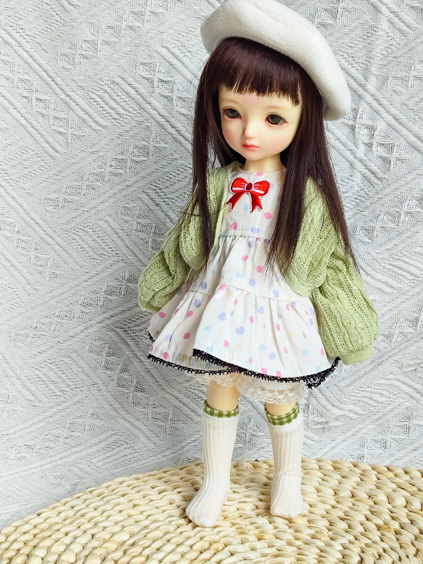 Side view of BJD doll in a chic polka dot dress and green knit cardigan.