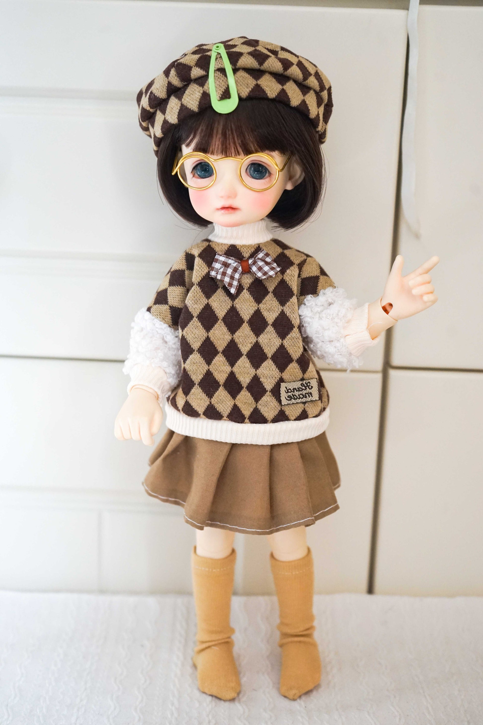 1/6 BJD YoSD doll in a preppy argyle knit vest and pleated skirt set.