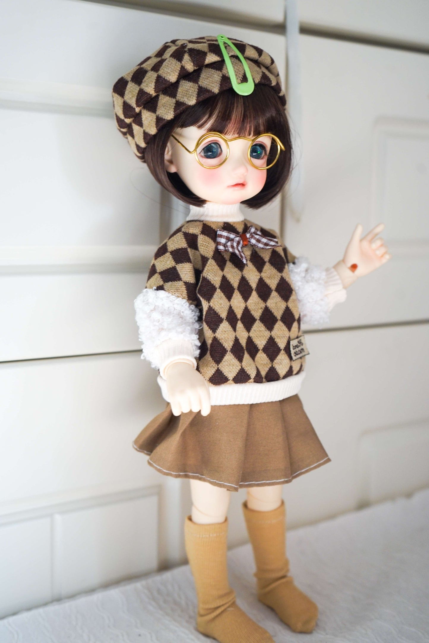 Side view of BJD doll wearing academic style argyle vest outfit.